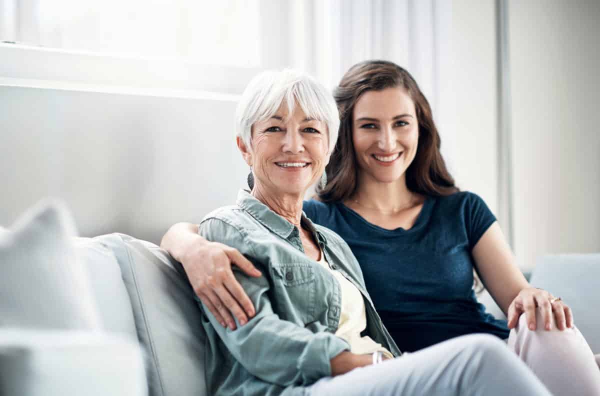 Portrait of a young woman and her elderly mother relaxing together on the sofa at home